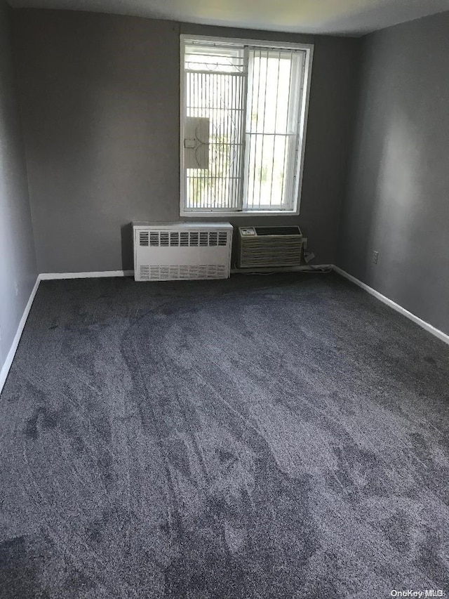 empty room with carpet, radiator heating unit, and an AC wall unit