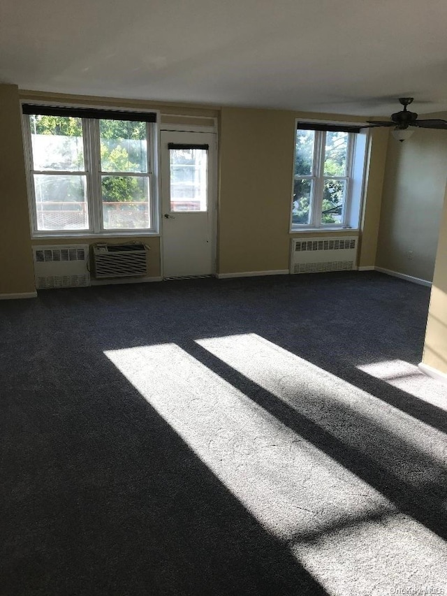 unfurnished room featuring dark colored carpet, radiator heating unit, and a wealth of natural light