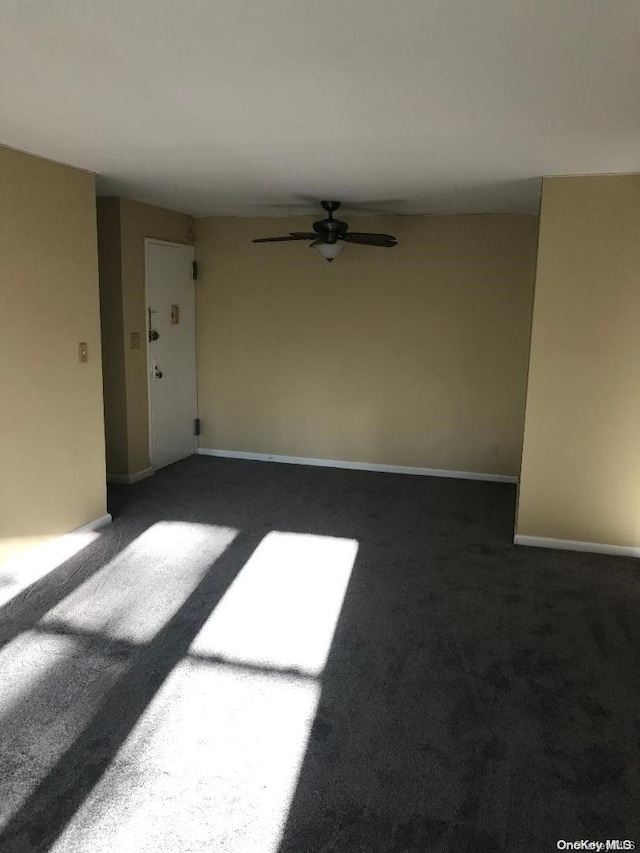 unfurnished room featuring ceiling fan and dark carpet