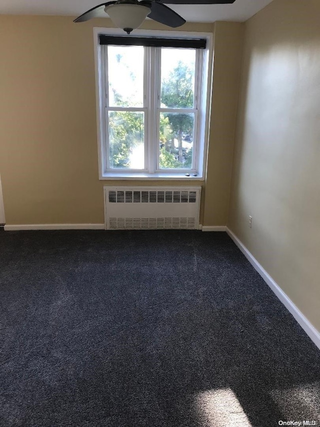 carpeted spare room featuring ceiling fan and radiator heating unit