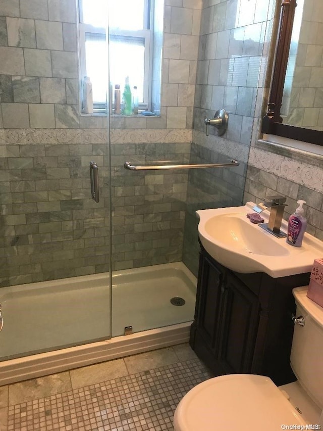 bathroom featuring tile patterned floors, walk in shower, vanity, tile walls, and toilet