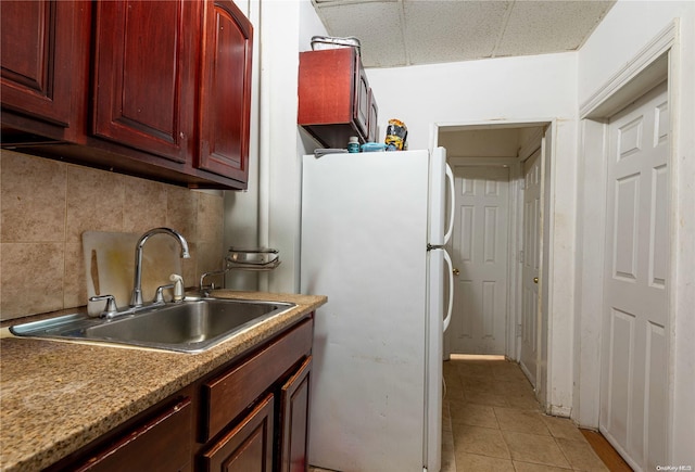 kitchen featuring backsplash, sink, light tile patterned floors, and white refrigerator