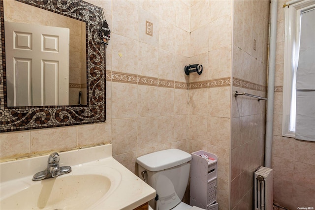 bathroom featuring vanity, toilet, radiator, and tile walls