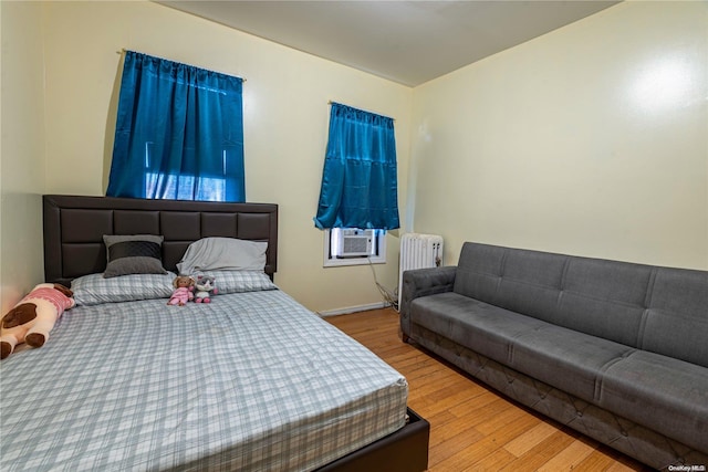 bedroom with radiator, cooling unit, and hardwood / wood-style flooring