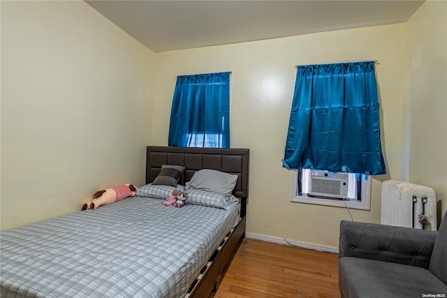 bedroom featuring light wood-type flooring, radiator, and cooling unit