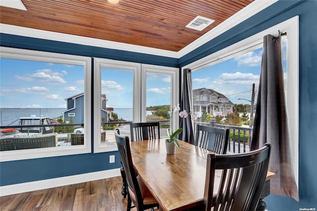 dining area with a water view, hardwood / wood-style flooring, a healthy amount of sunlight, and wood ceiling