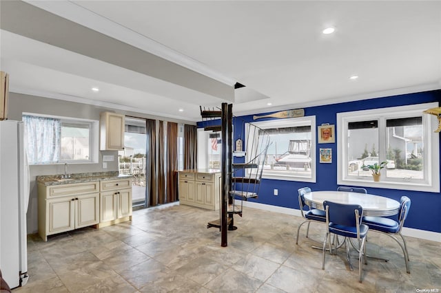 interior space featuring cream cabinets, white refrigerator, ornamental molding, and sink