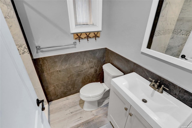 bathroom featuring vanity, toilet, and tile walls