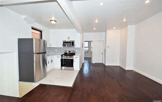 kitchen with white cabinets, light hardwood / wood-style flooring, decorative backsplash, beam ceiling, and stainless steel appliances