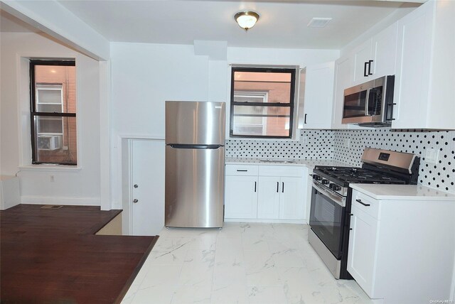 kitchen featuring white cabinets, stainless steel appliances, and tasteful backsplash