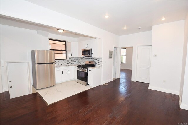 kitchen featuring electric panel, white cabinets, decorative backsplash, light wood-type flooring, and appliances with stainless steel finishes