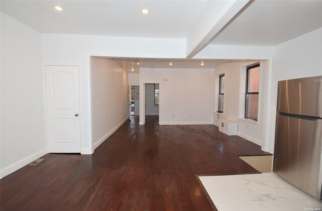 unfurnished living room featuring beamed ceiling and hardwood / wood-style flooring