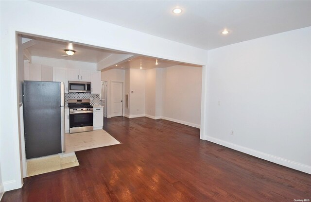 kitchen featuring white cabinets, backsplash, stainless steel appliances, and dark wood-type flooring