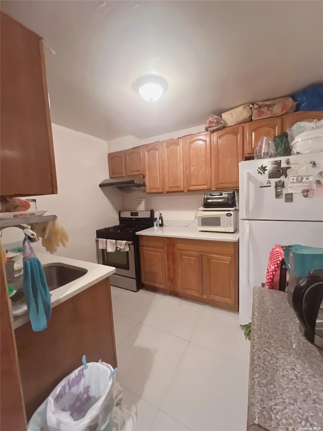 kitchen with light tile patterned floors, white appliances, and sink