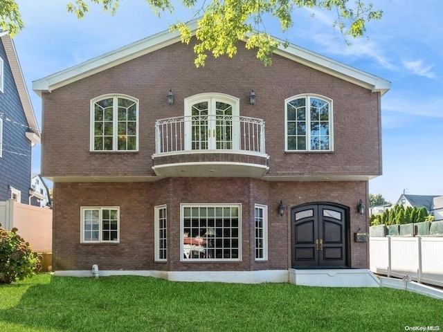 back of property featuring a balcony and a lawn