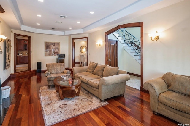 living room featuring a raised ceiling and dark wood-type flooring