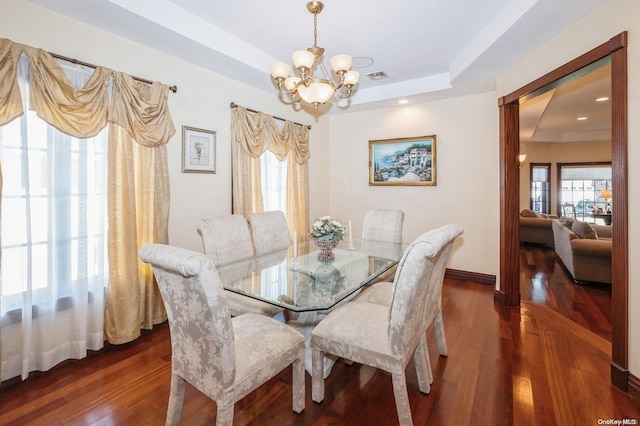 dining room featuring a notable chandelier, dark hardwood / wood-style flooring, and a tray ceiling