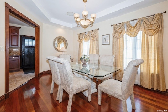 dining room featuring a chandelier, dark wood-type flooring, and a tray ceiling