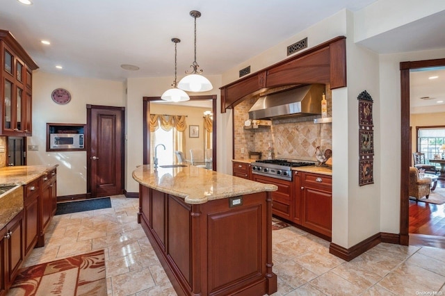 kitchen with a center island with sink, hanging light fixtures, range hood, tasteful backsplash, and stainless steel appliances