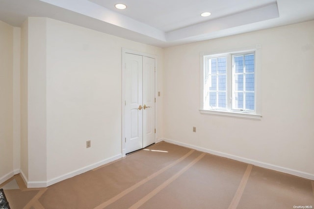 carpeted spare room featuring a tray ceiling