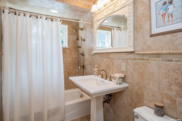 bathroom featuring tile walls, shower / bath combo, and toilet