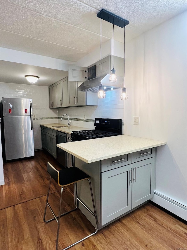 kitchen with pendant lighting, black appliances, kitchen peninsula, sink, and gray cabinetry