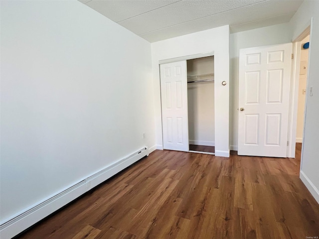 unfurnished bedroom with a closet, dark hardwood / wood-style floors, and a baseboard radiator