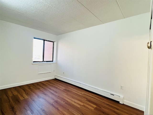 unfurnished room with baseboard heating and dark wood-type flooring