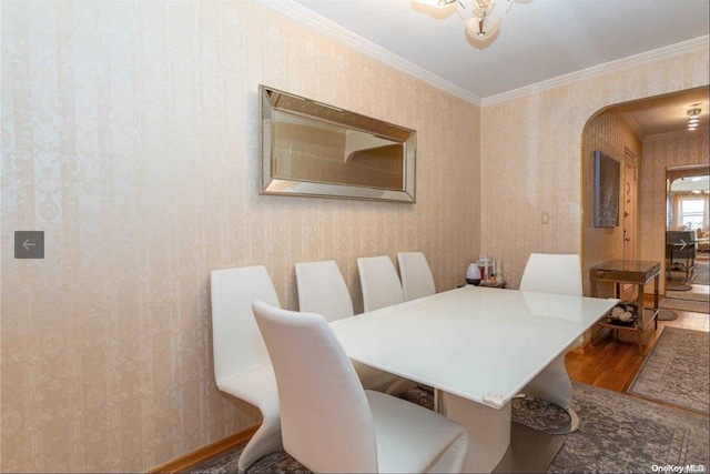 dining room with crown molding, hardwood / wood-style floors, and an inviting chandelier