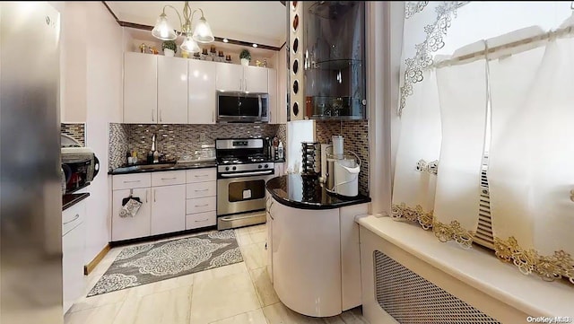 kitchen featuring appliances with stainless steel finishes, backsplash, light tile patterned floors, white cabinetry, and hanging light fixtures