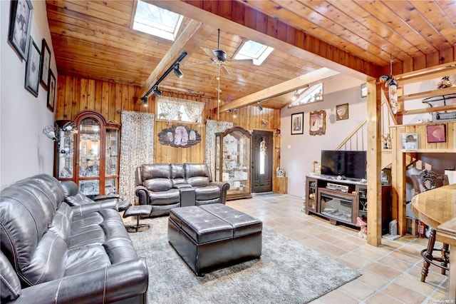 tiled living room featuring ceiling fan, beam ceiling, wooden ceiling, and a skylight