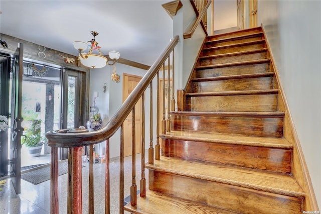 staircase with an inviting chandelier