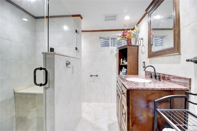 bathroom featuring vanity, a shower with door, ornamental molding, and tile walls