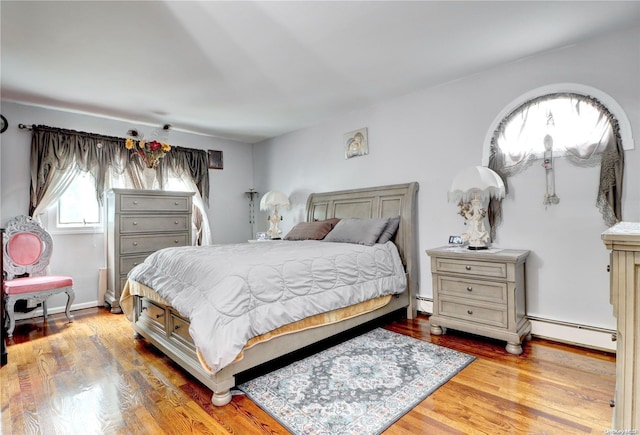 bedroom featuring baseboard heating and light hardwood / wood-style flooring