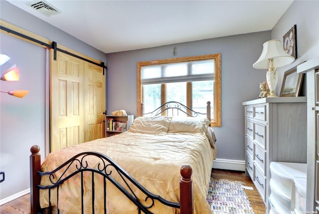 bedroom featuring a barn door, a closet, and dark wood-type flooring