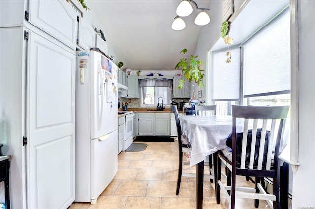 kitchen featuring decorative backsplash, white appliances, sink, light tile patterned floors, and white cabinets