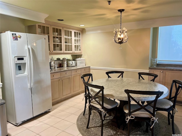 dining space with crown molding, light tile patterned flooring, and a notable chandelier