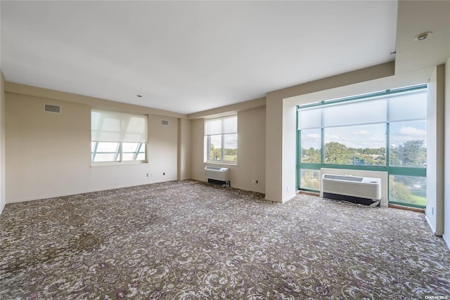 empty room featuring a wall mounted AC, heating unit, and carpet