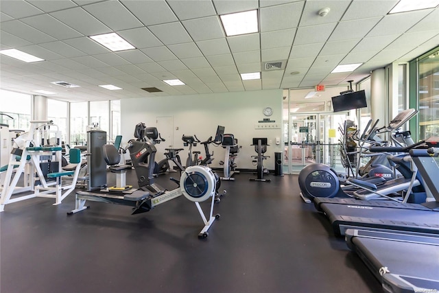 exercise room with a wall of windows and a drop ceiling