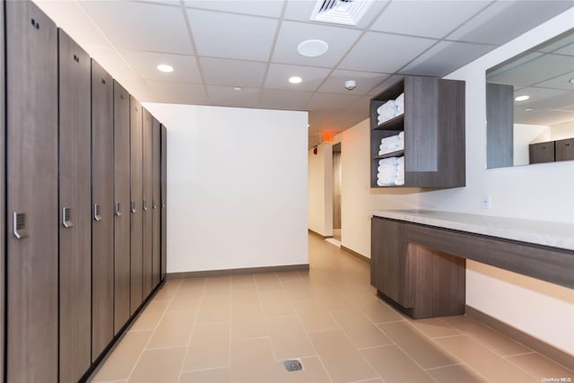 interior space with a drop ceiling and light tile patterned floors