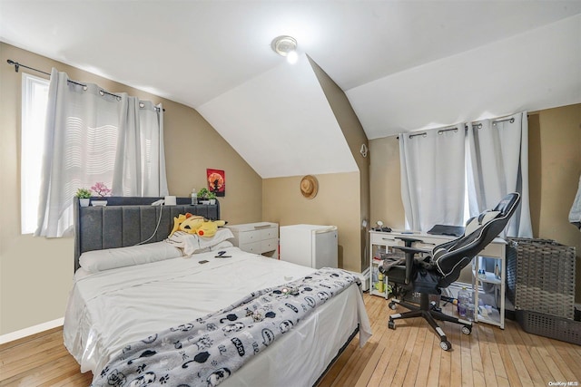 bedroom featuring light hardwood / wood-style floors, vaulted ceiling, and white refrigerator