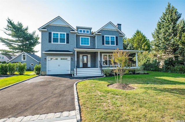 view of front of home with covered porch, a garage, and a front lawn