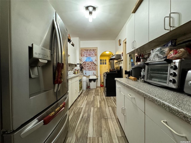 kitchen with white cabinetry, stainless steel fridge with ice dispenser, light hardwood / wood-style flooring, and gas stove