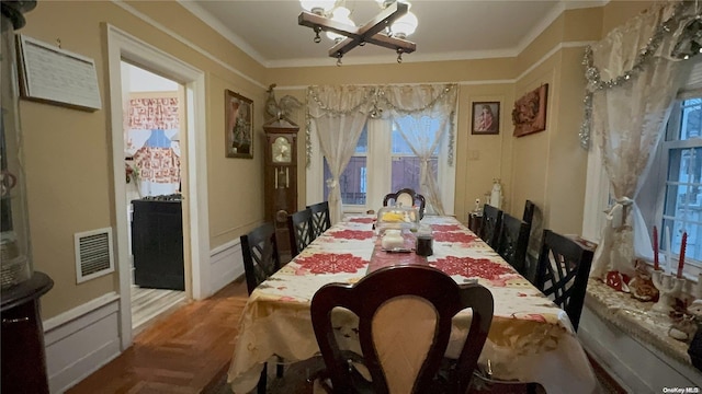 dining room with crown molding, light parquet floors, and a notable chandelier