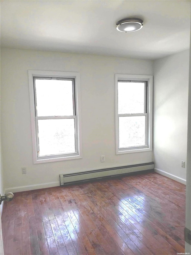 spare room with a healthy amount of sunlight, dark wood-type flooring, and a baseboard radiator