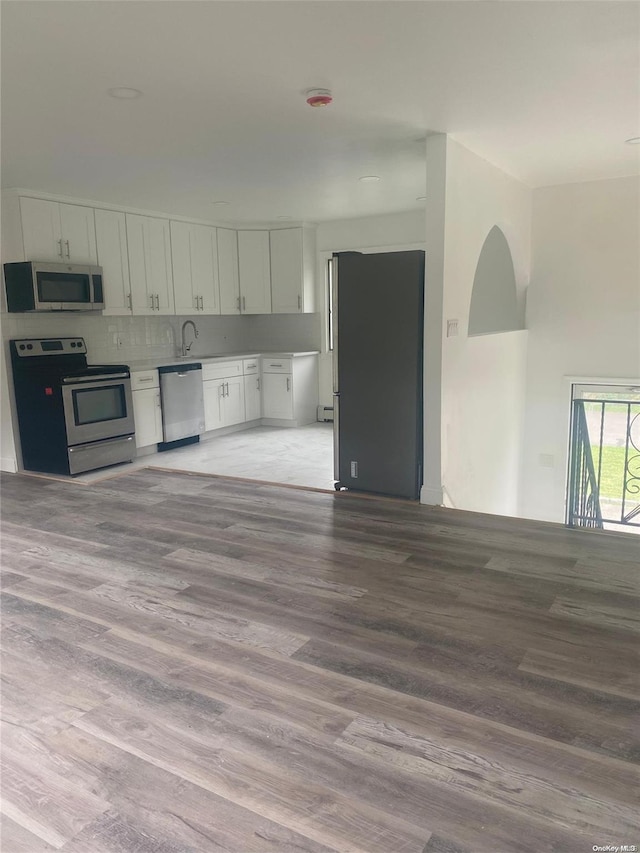 kitchen with white cabinets, backsplash, stainless steel appliances, and light hardwood / wood-style floors