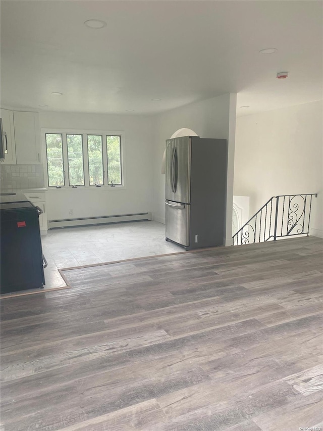 unfurnished living room featuring light hardwood / wood-style floors and a baseboard heating unit