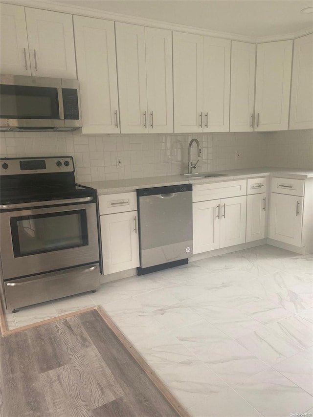 kitchen featuring backsplash, sink, white cabinets, and appliances with stainless steel finishes