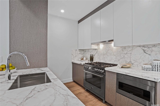 kitchen with light stone countertops, white cabinetry, sink, and appliances with stainless steel finishes