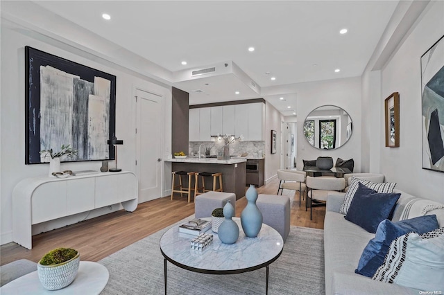 living room featuring sink and light hardwood / wood-style flooring